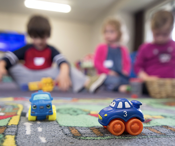 Toy cars with three children in the background